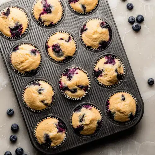 Greek Yogurt Blueberry Protein Muffins 4 Greek yogurt blueberry protein muffins in a muffin tin on stone countertop