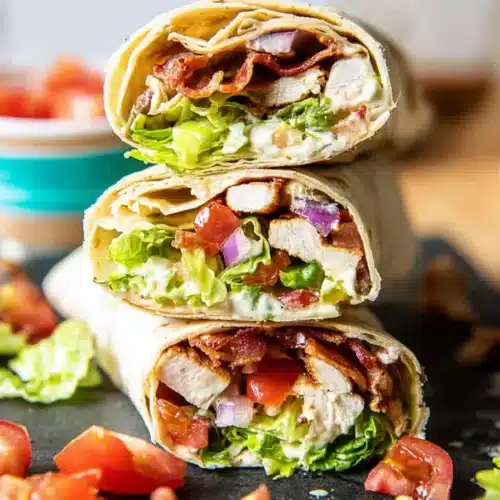 Chicken bacon ranch wrap halves stacked with lettuce tomato bacon and grilled chicken